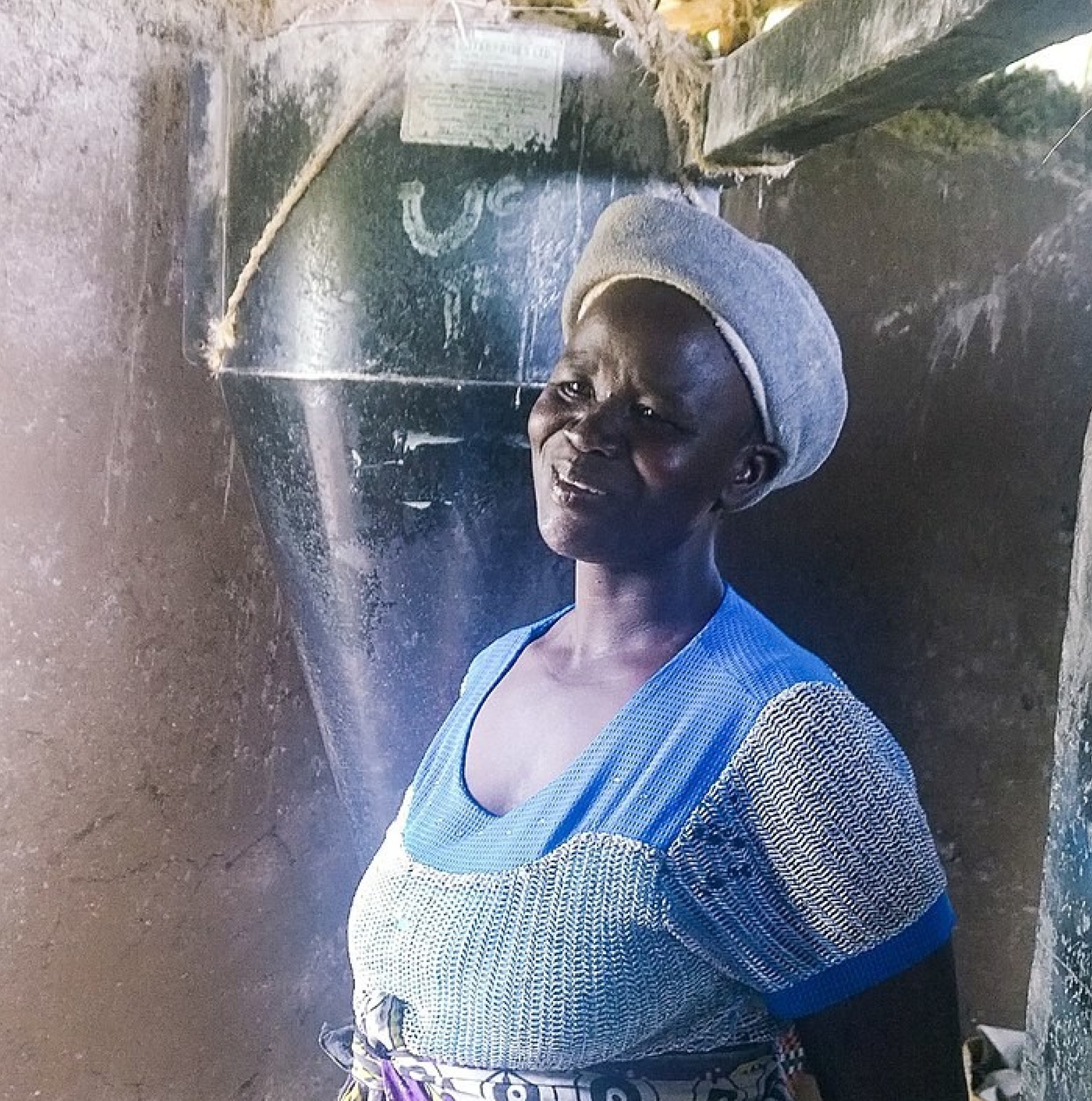 A Kenyan lady next to a Posho mill, used to mill cowpea seed into flour 