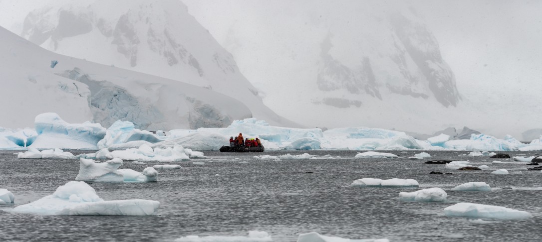Antactica - a small dinghy on the ocean, surrounded by ice and mountains