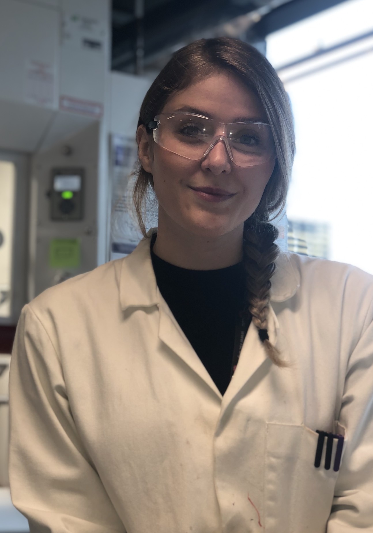 Woman in lab coat and safety goggles
