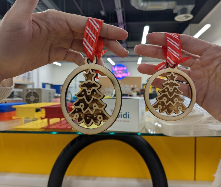 two laser cut christmas baubles with ribbon, christmas tree engraved on them