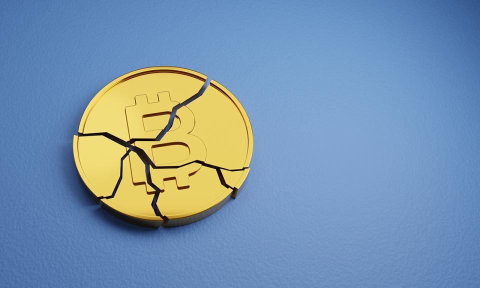 A broken Bitcoin token against a blue background