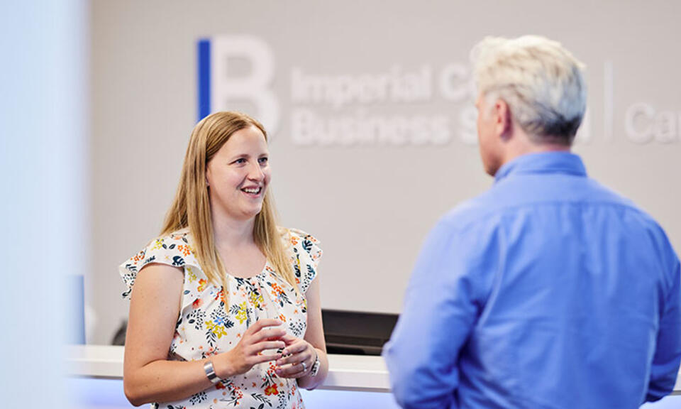 Two people standing in front of the Imperial College Business School careers service desk