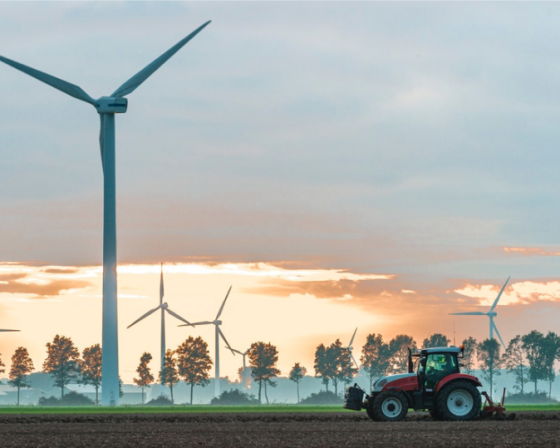 A windfarm behind a tractor ploughing a field