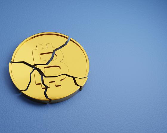 A broken Bitcoin token against a blue background