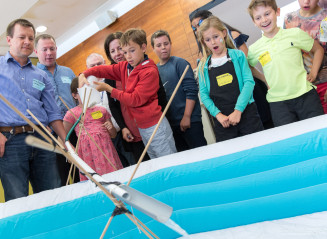 group of children around inflatable pool with device made of sticks 