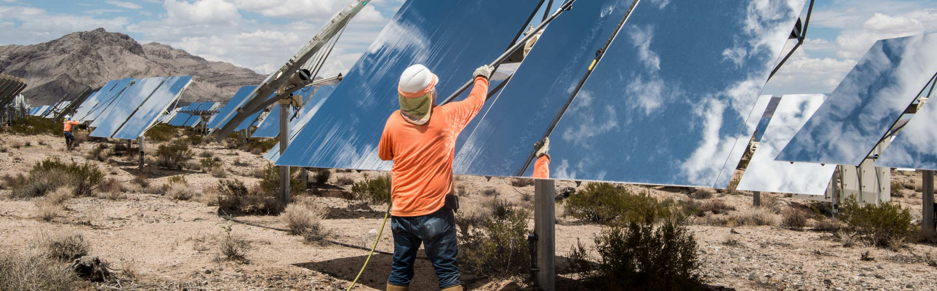 man cleaning big solar panels installed on the floor in arid conditions