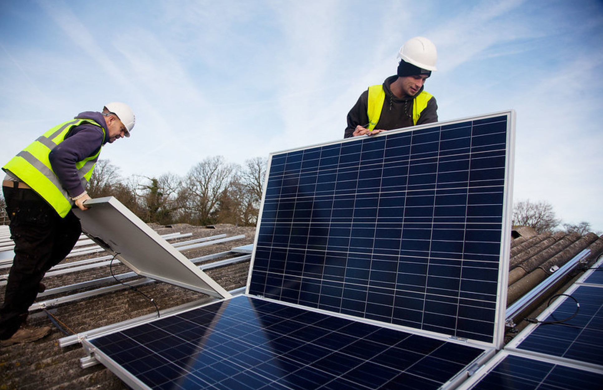 Andy Tyrrell and Jake Beautyman install solar panels on a barn roof on Grange farm, near Balcombe - c - Kristian Buus - Licensed under 2.0 Generic CC BY 2.0