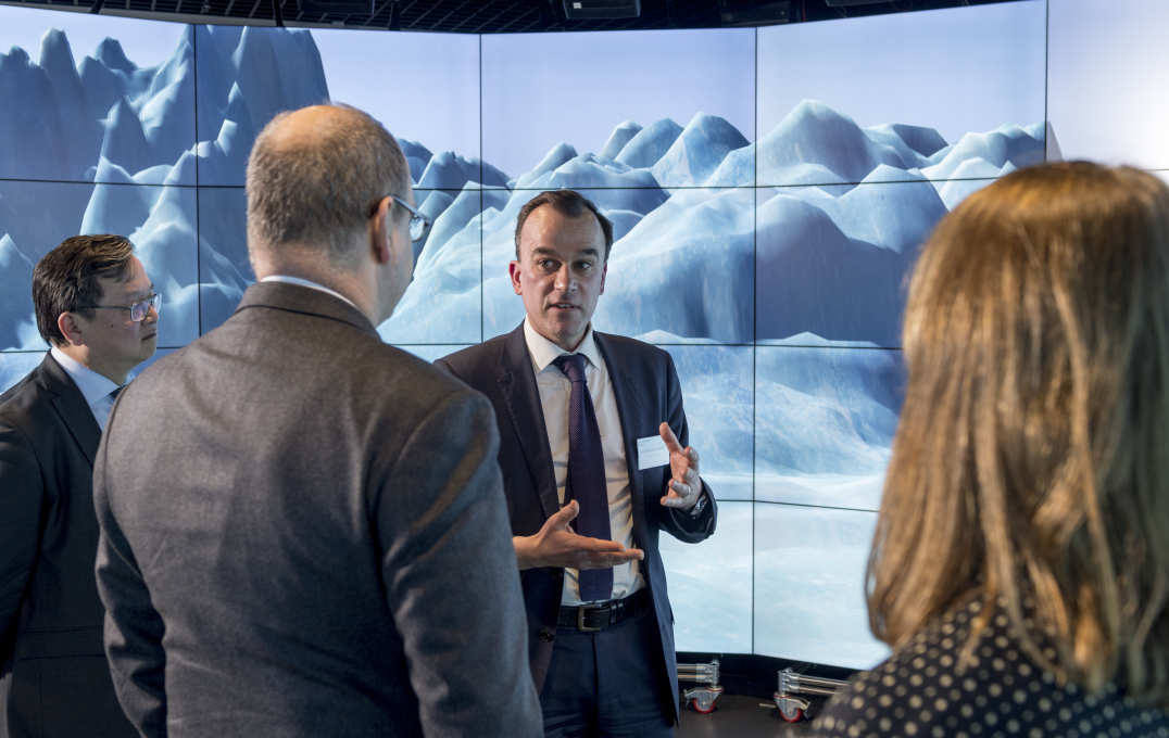 Martin Siegert speaks to the prince in front of a large screen showing Antarctic landscape