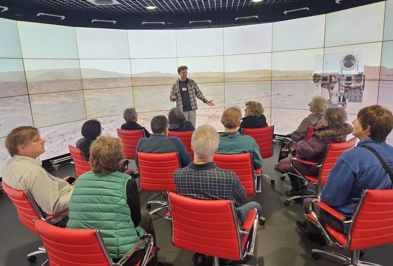 Alex Jones standing in front of the observatory screens in front of a crowd of Open Age members