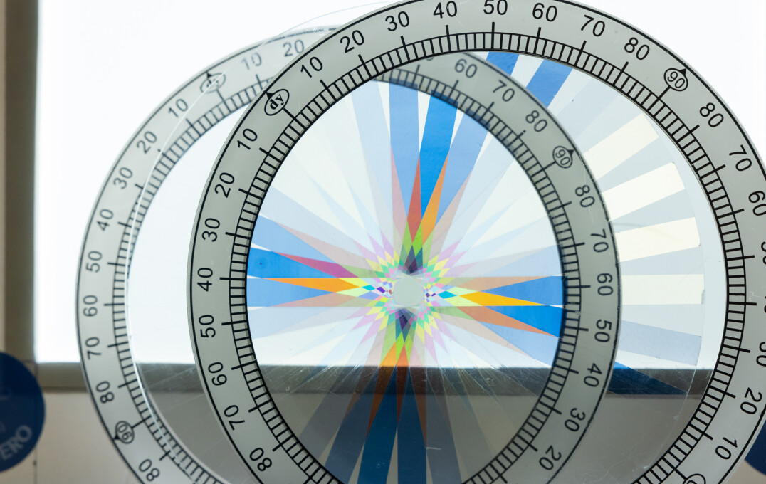 Overlapping transparent protractors with angular measurements,creating a colorful, symmetrical starburst pattern. 