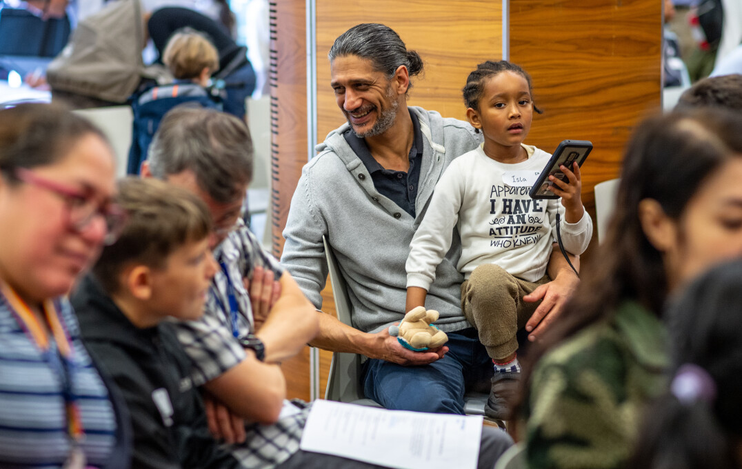 A man holding his child on his lab in a packed audience