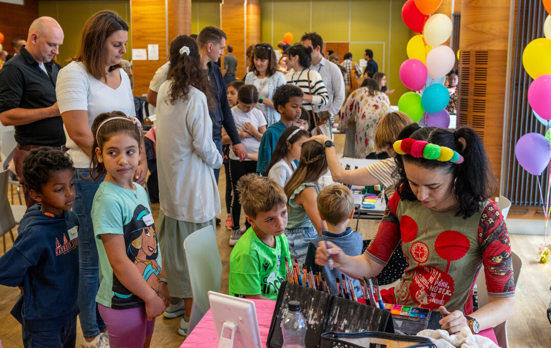A busy room with a child getting their face painted in the foreground