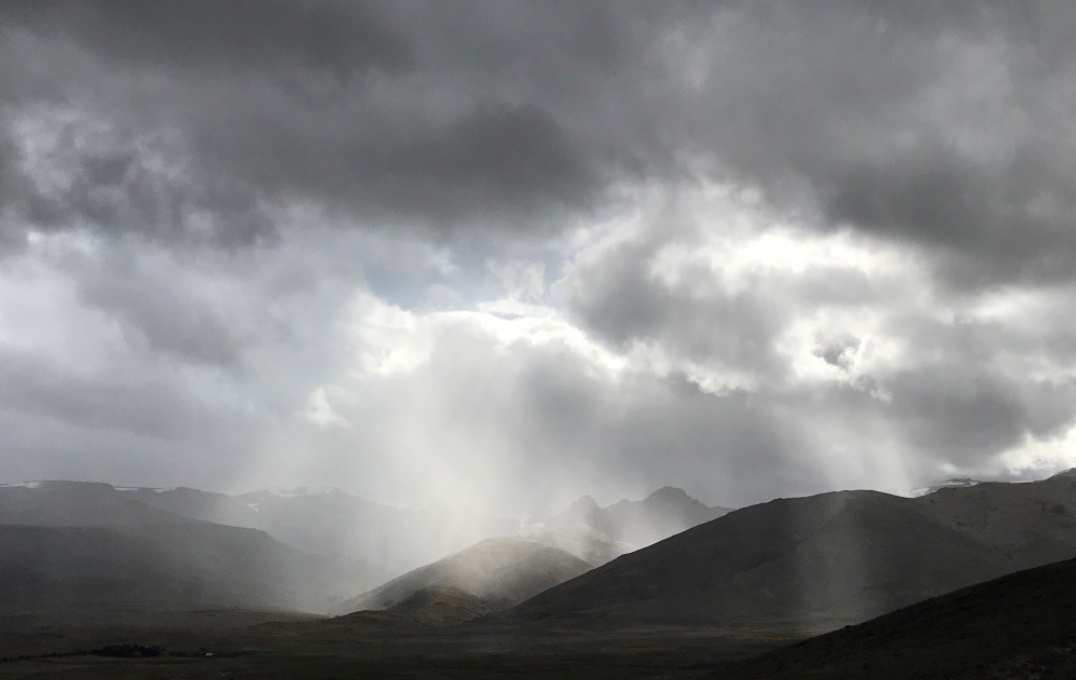 Rays of sunshine streaming through dark clouds over hills in Argentina, on earth science fieldwork