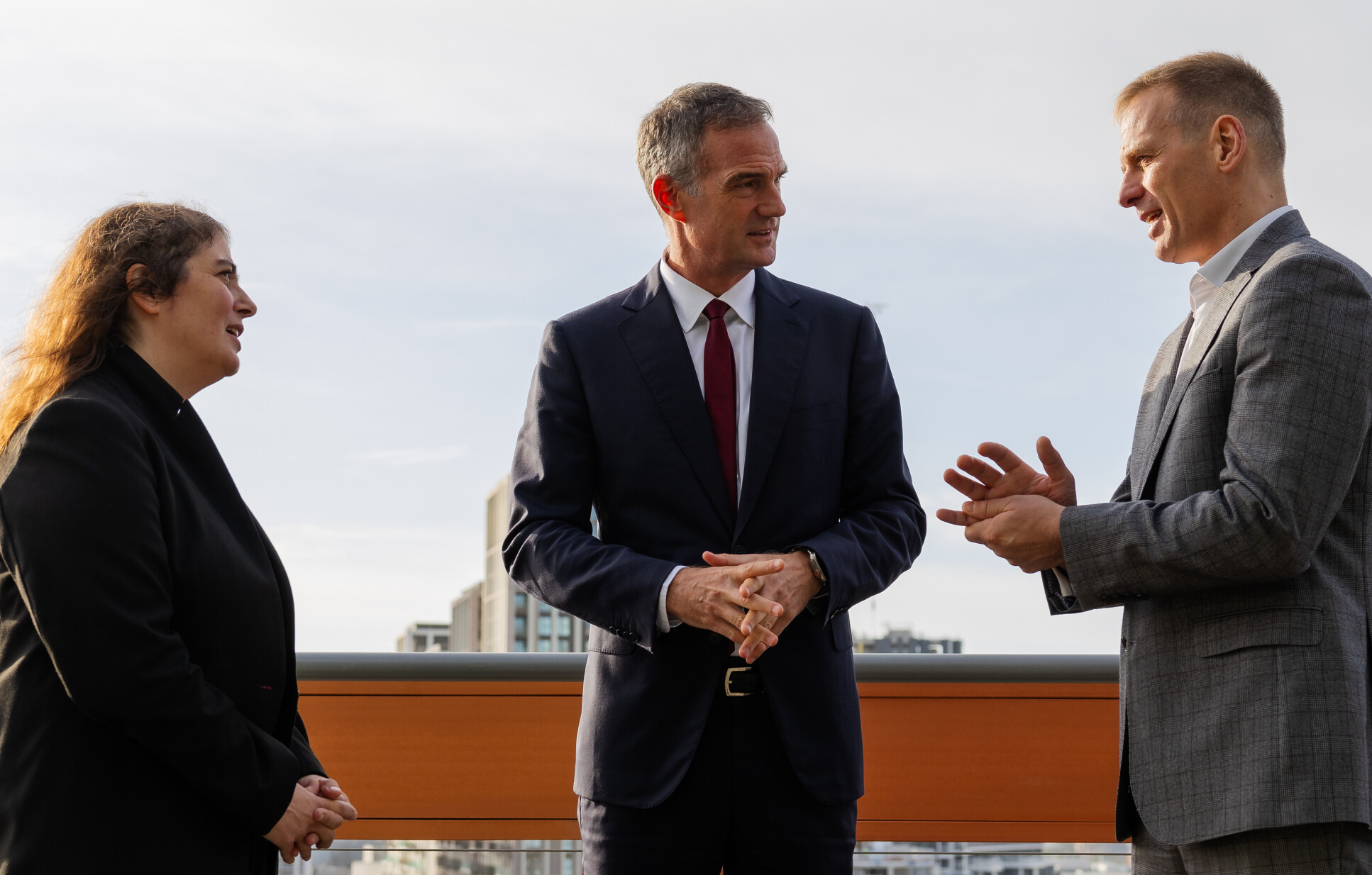 Professor Karen Polizzi, Dr Peter Kyle MP and Professor Anthony Bull talking to each other on the terrace of Imperial's I-HUB building