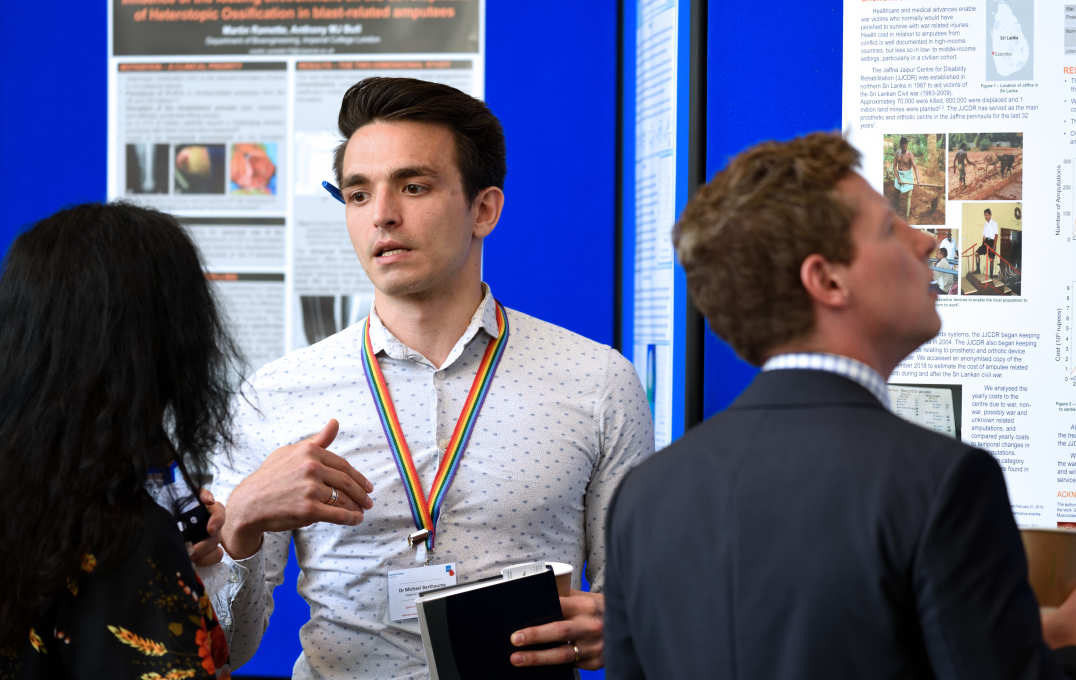 Dr Michael Berthaume explaining his work in front of a poster of his work to a female delegate
