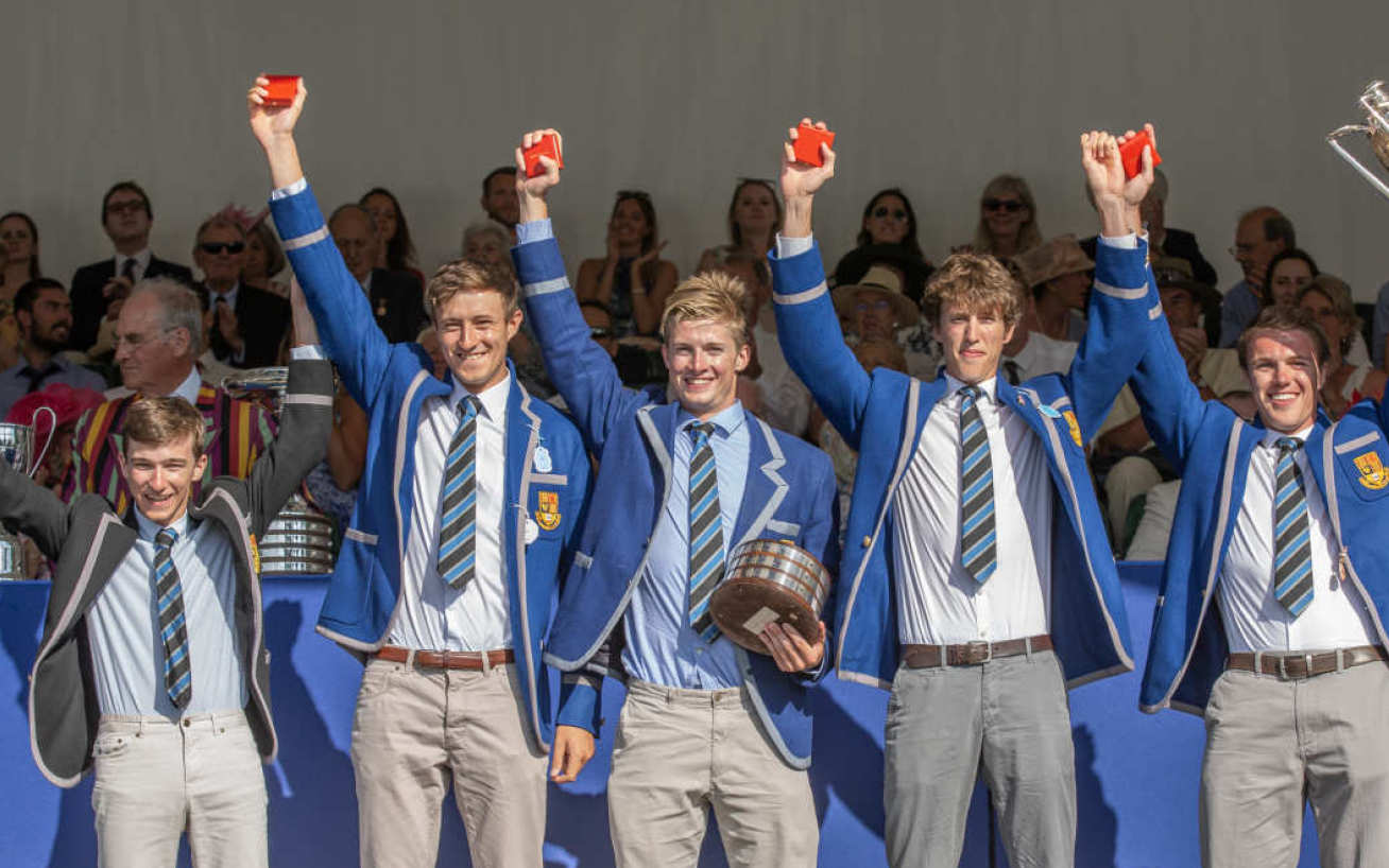 Men from the Boat Club wearing official blazers and standing in line with river in background