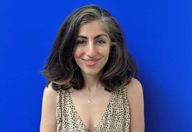 Photo of Dr Parry Hashemi in front of a blue display board