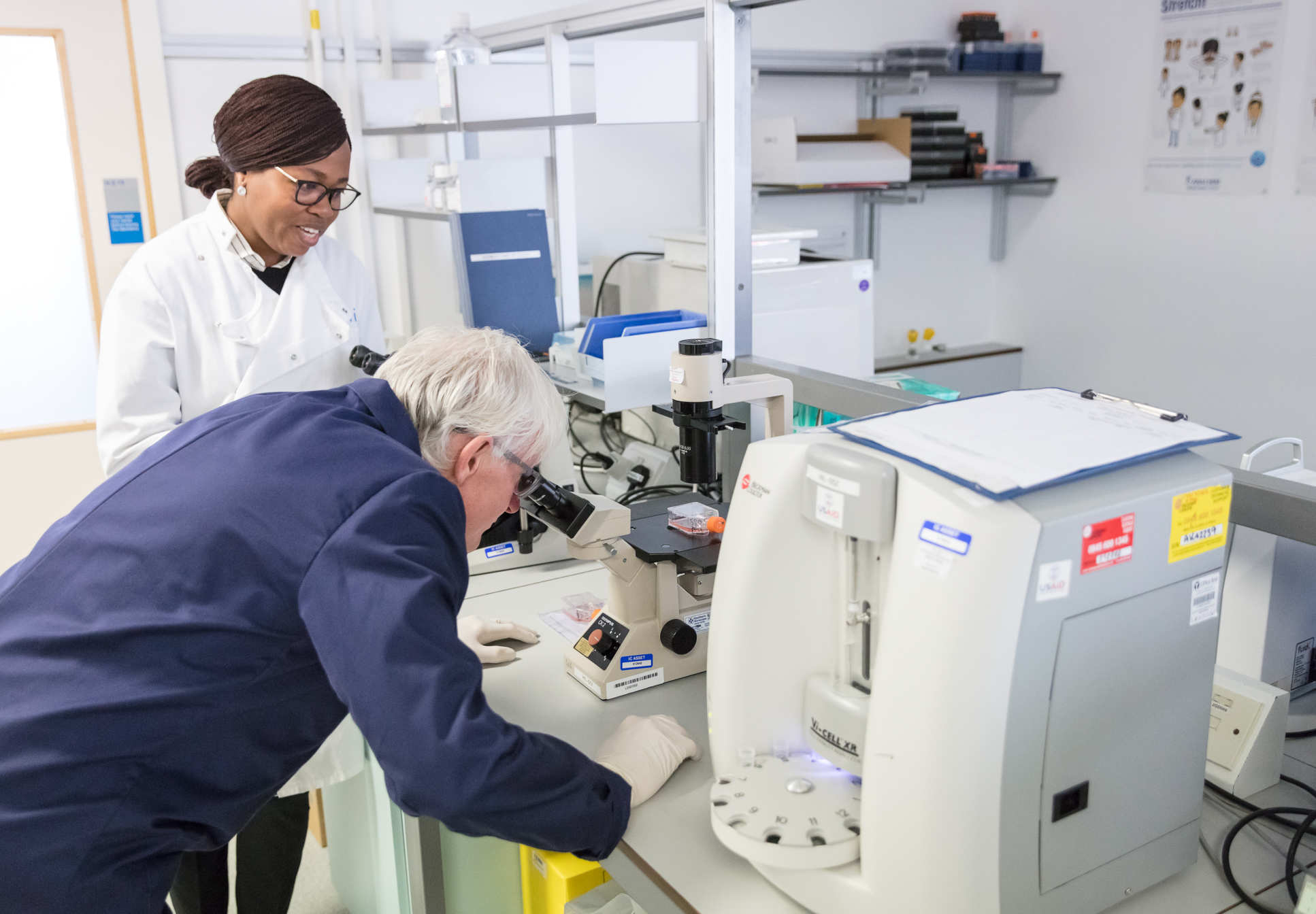 Norman Lamb MP looks down a microscope with Dr Julia Makinde
