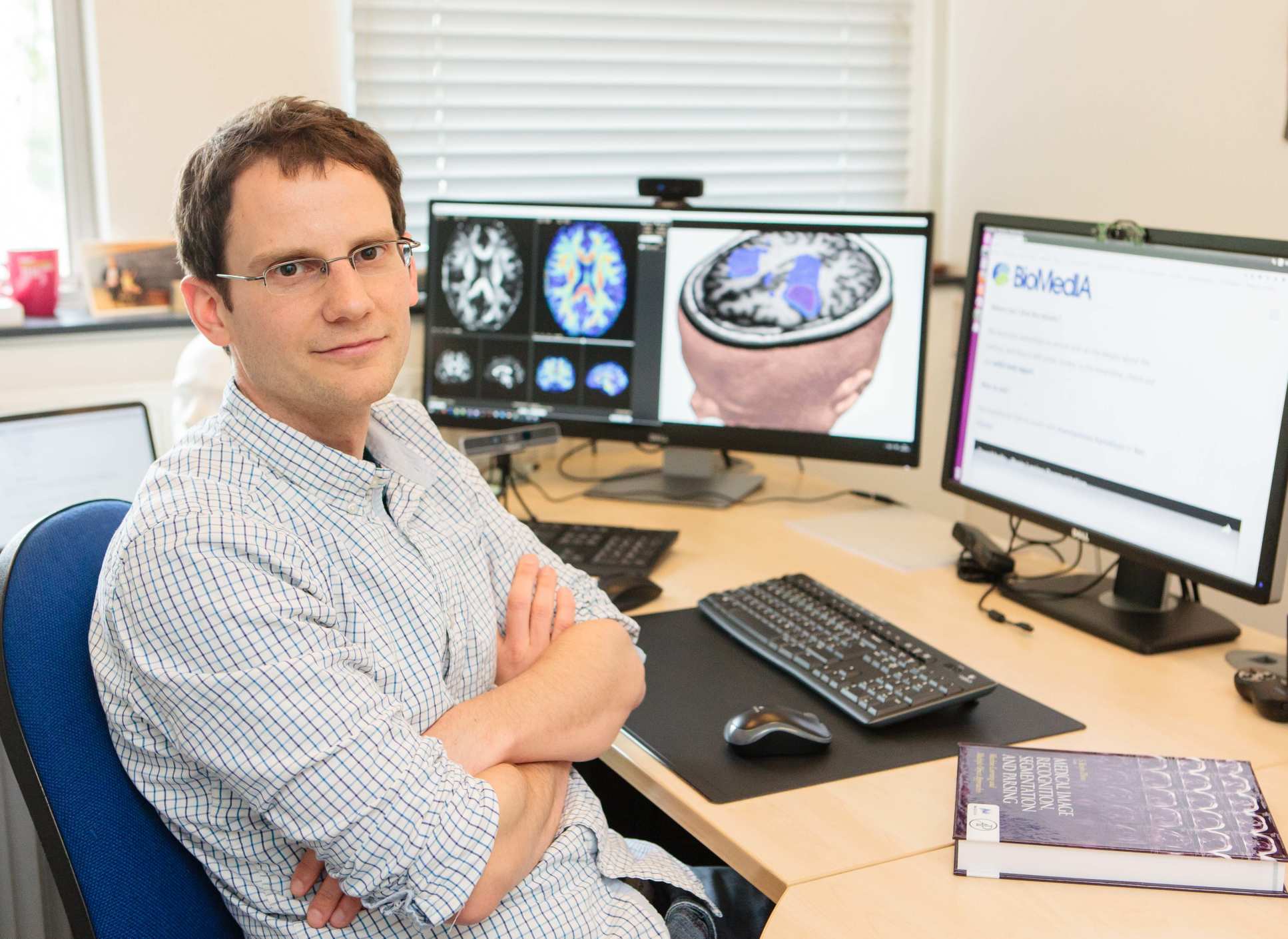 Dr Ben Glocker seated at a computer showing medical scans