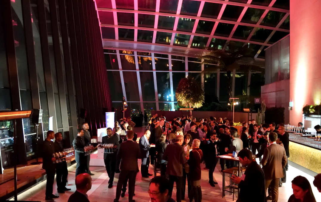 Alumni and guests mingle in front of huge windows overlooking the London skyline at night