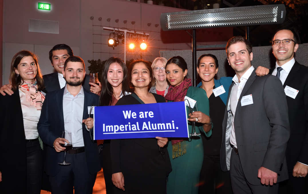 A group of alumni smiling at the camera, holding a banner that reads 'We are Imperial alumni'
