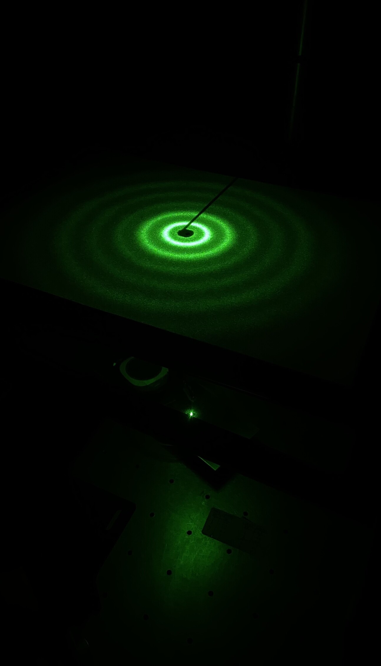  thin, standard polymer develops labyrinth-like surface patterns when subjected to plasma. When a green laser is directed onto the surface, the light diffracts, and the resulting diffraction pattern is projected onto a screen as concentric rings