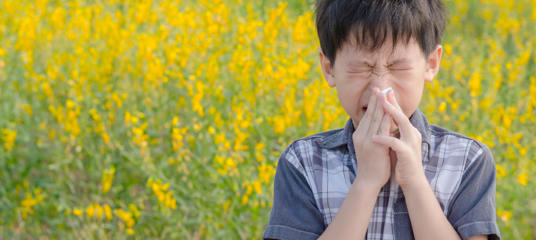 Boy sneezing in field