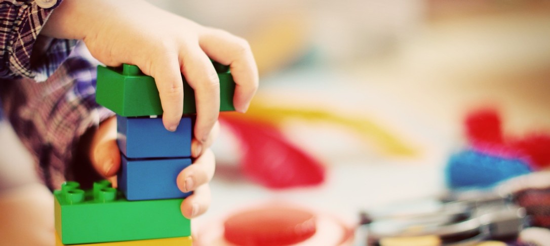 child's hand playing with toy bricks