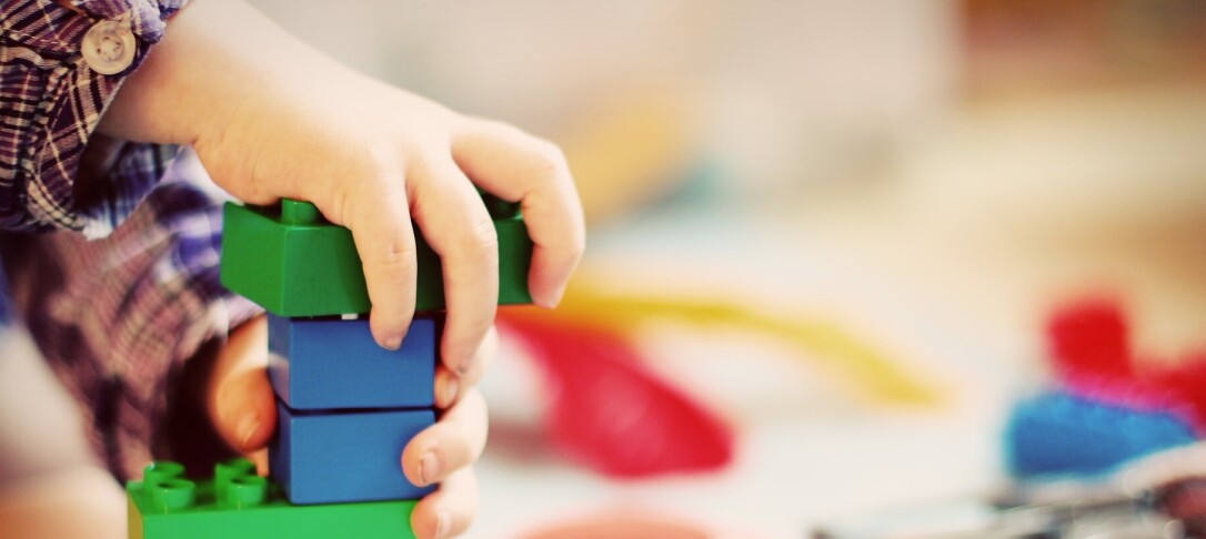 child's hand playing with plastic bricks