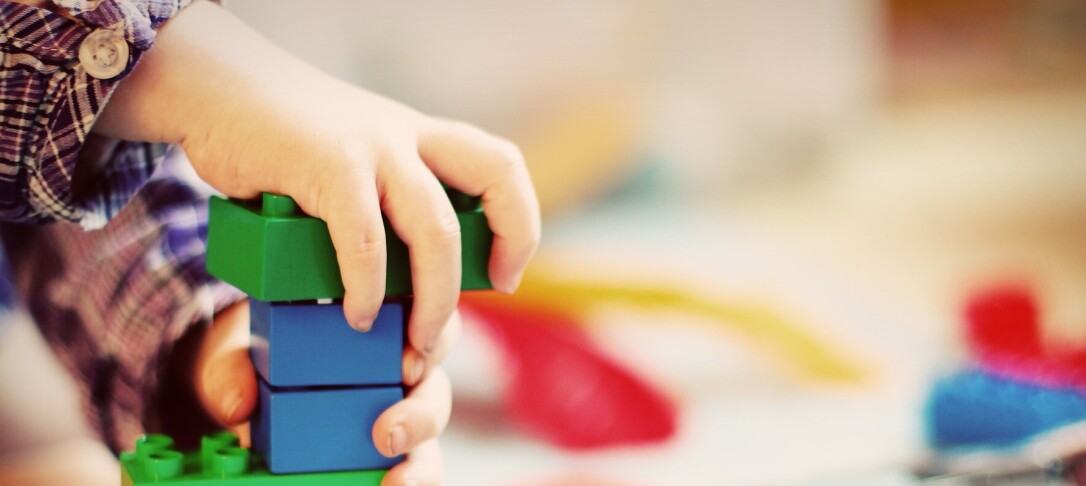 child's hand playing with coloured plastic bricks