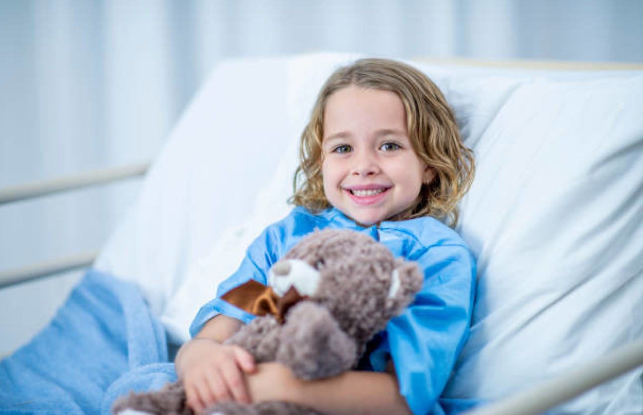 Little girl in a hospital bed with a teddy bear