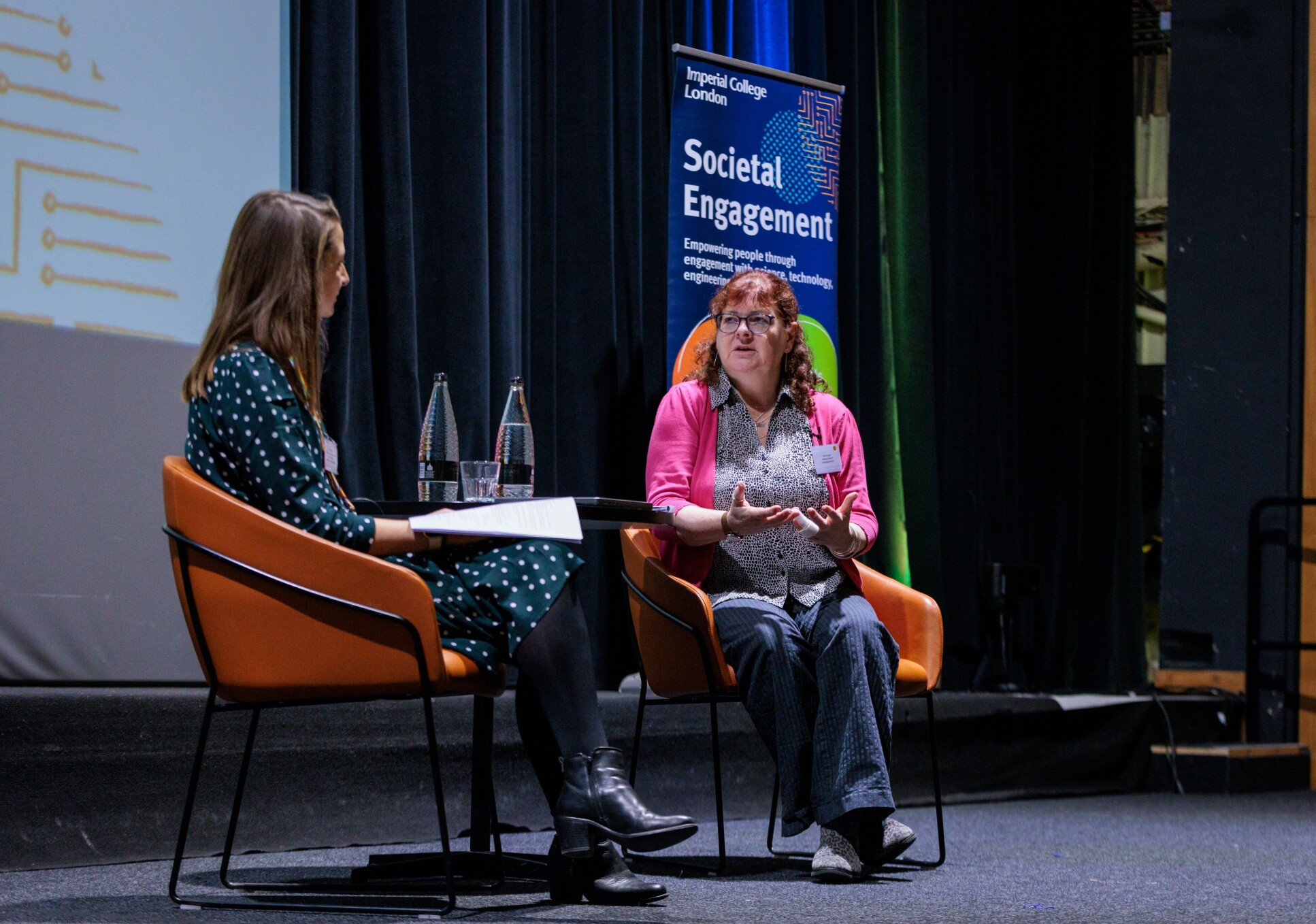 Two women sitting on stage in chairs at a Q&A