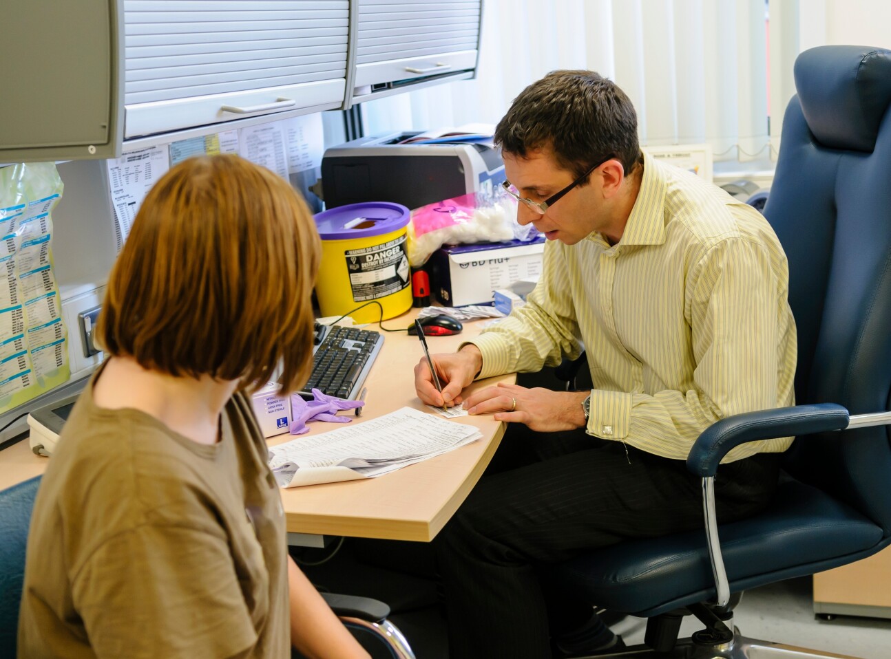 GP writing notes in front of a patient