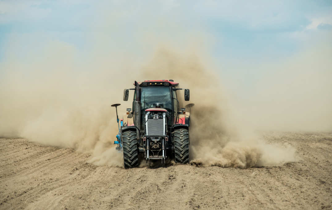 Tractor ploughs a dry field