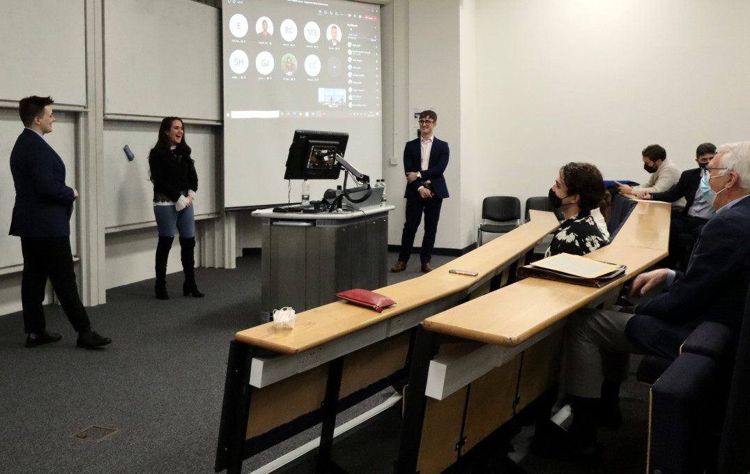 Two women and one man standing at the front of a lecture theatre