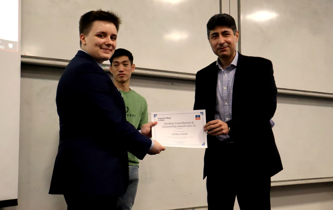 Man and woman smiling at the camera holding an award certificate