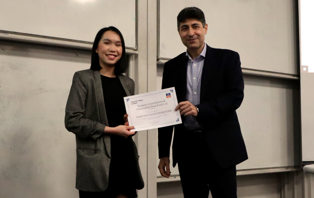 Man and woman smiling at the camera holding an award certificate