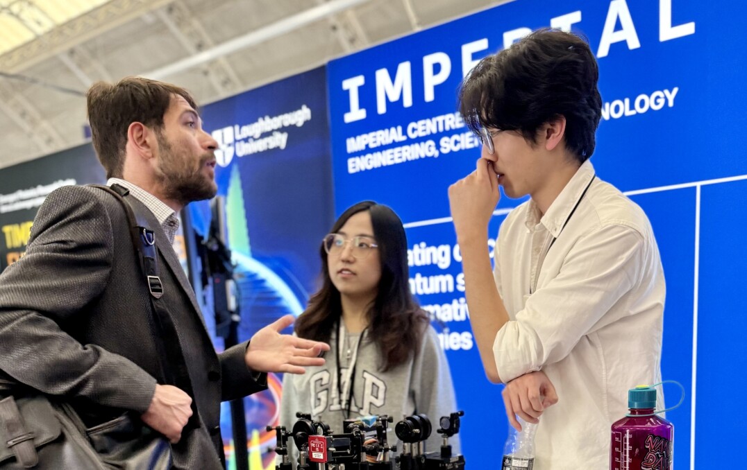 Participants talk to attendees at the QuEST stand