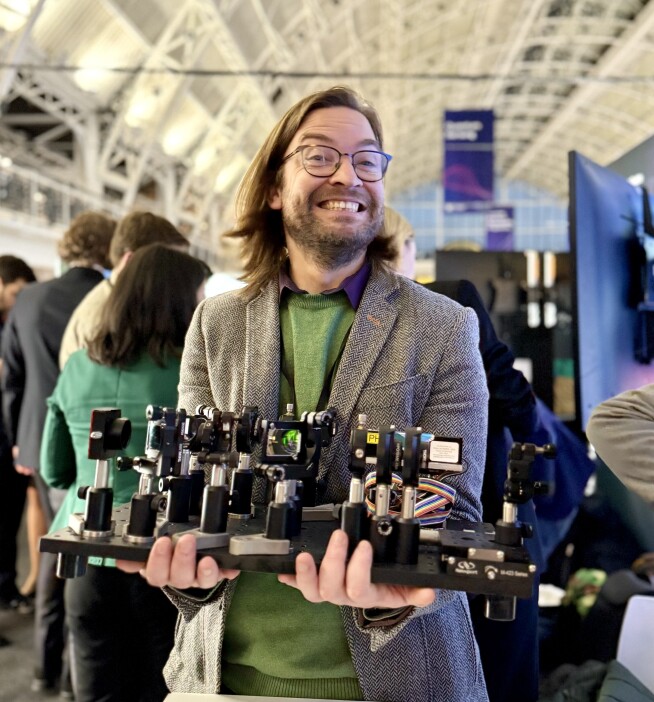 Nathan Gemmel, a member of the QuEST, poses with his quantum optics set up.