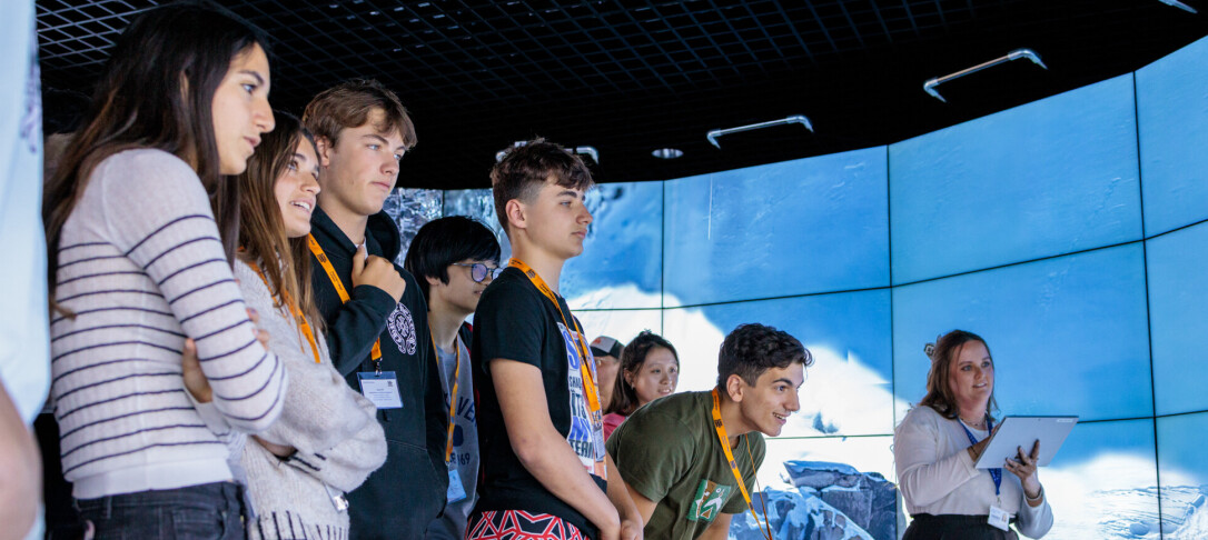 Teacher explaining task to two students at the global summer school