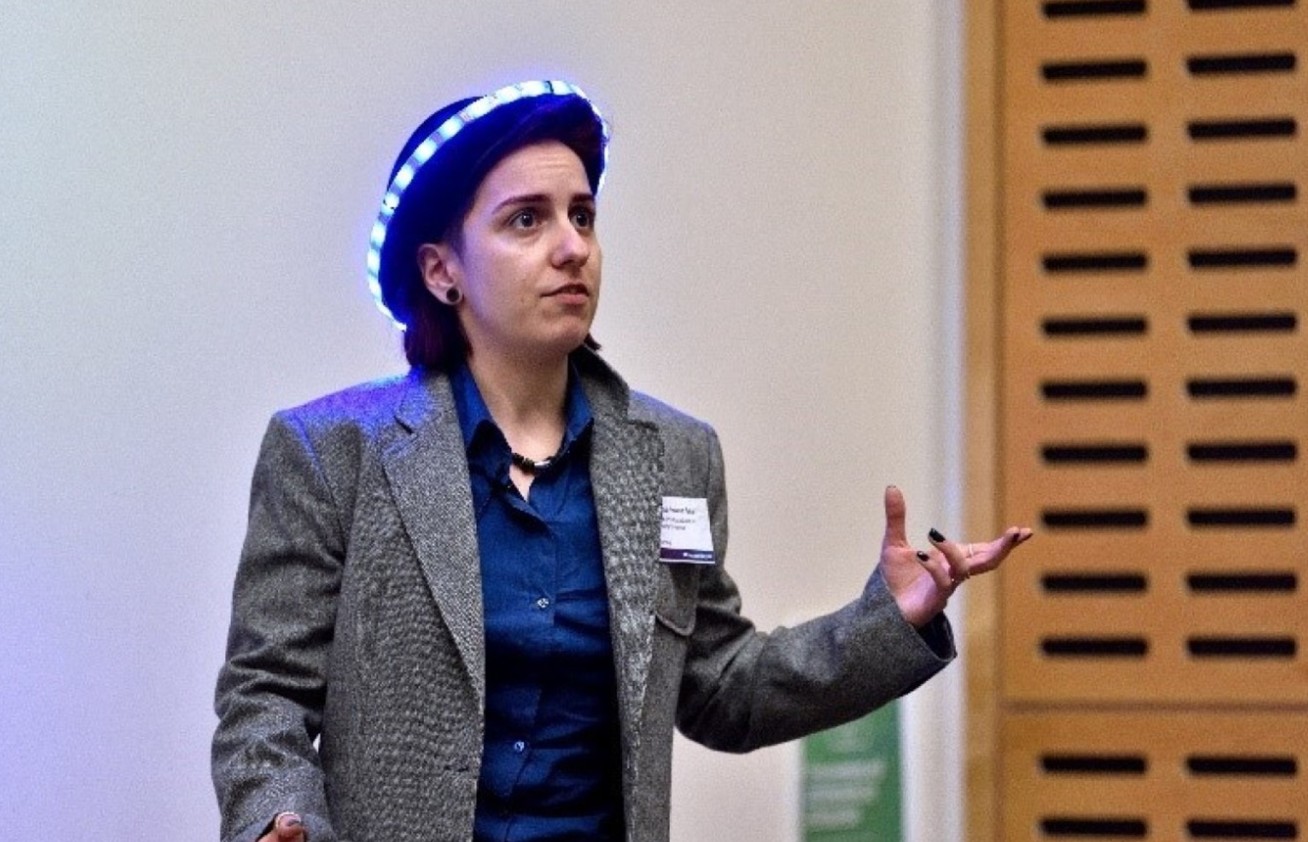 A woman speaking while wearing a light-up bowler hat