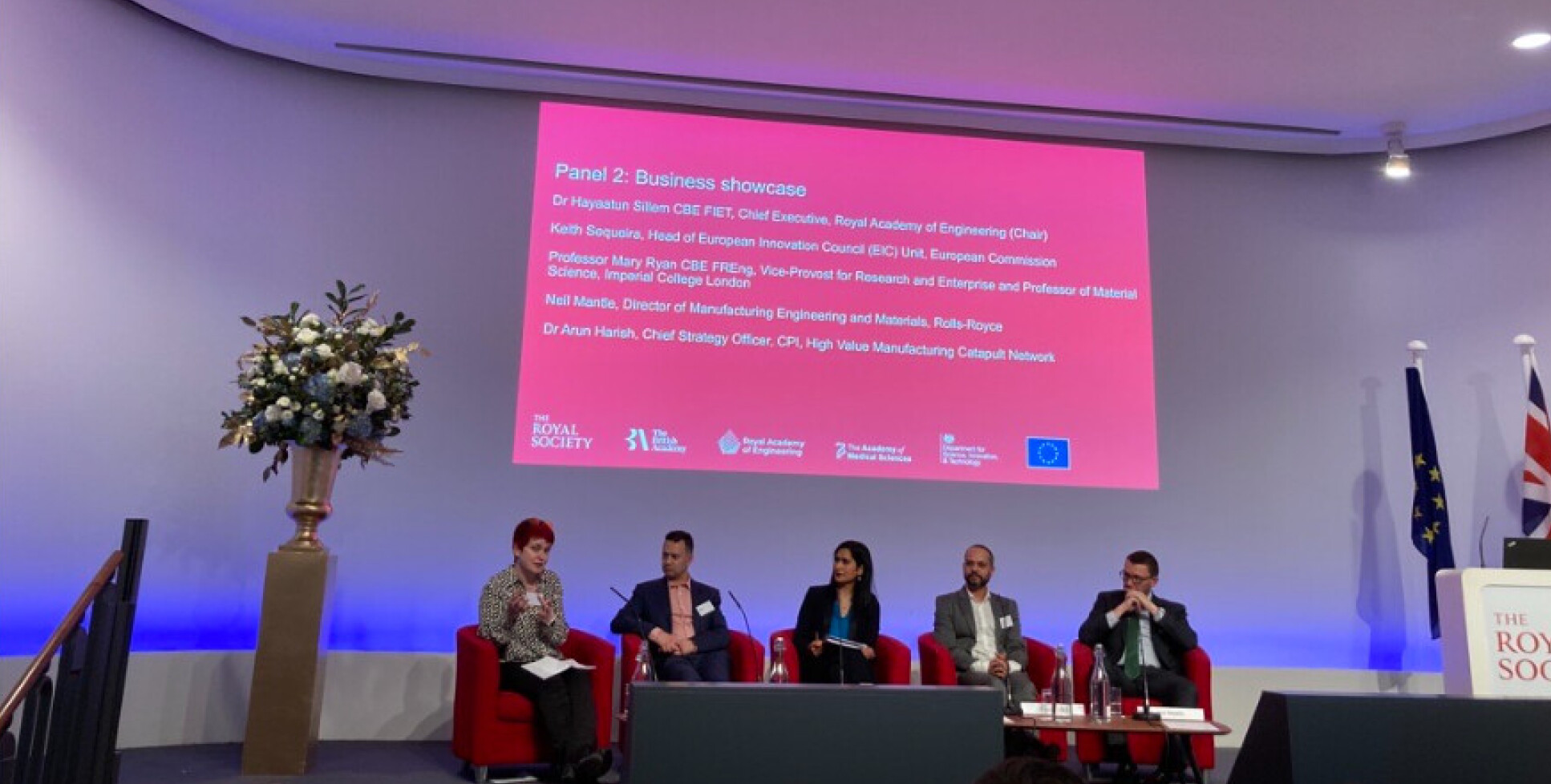 Professor Mary Ryan sitting down on a stage with four other people speaking during the panel session