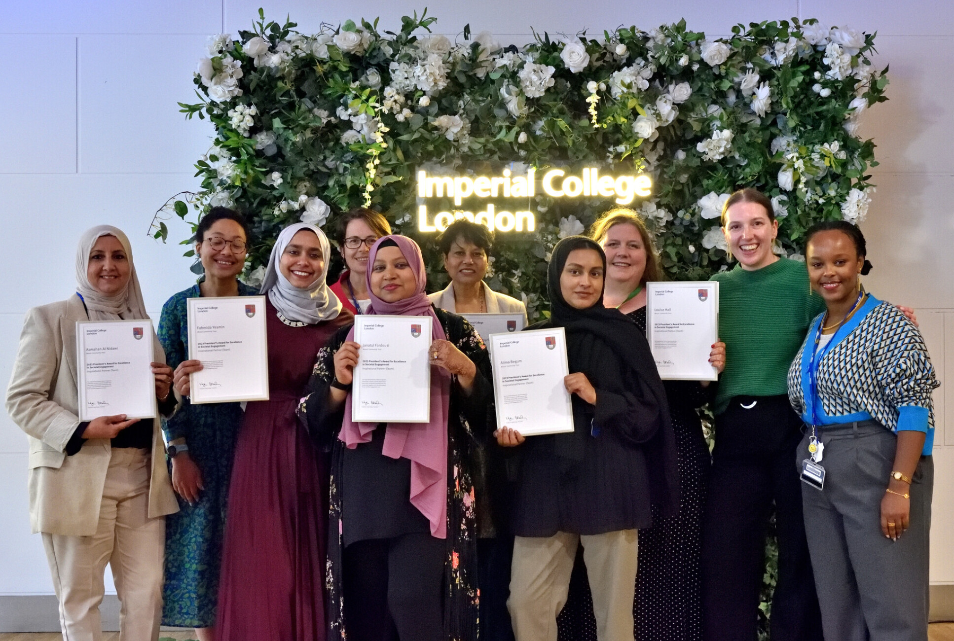 A group of ten women holding awards in front of an Imperial College London sign