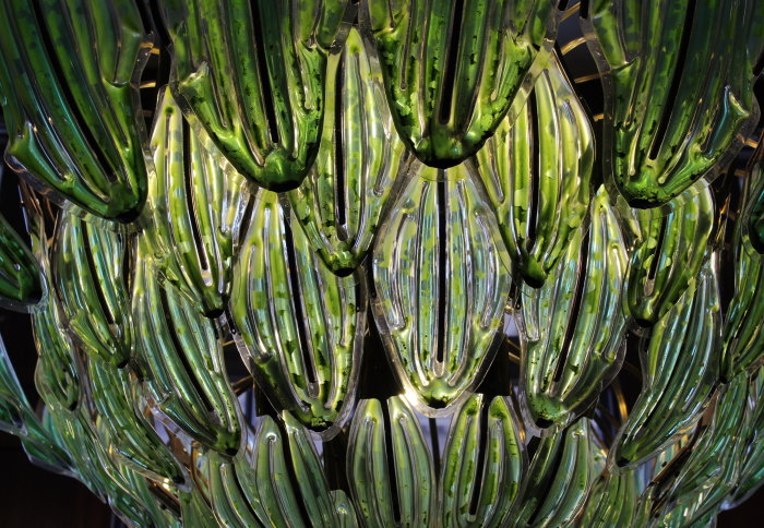 A green chandelier, made up of leaf-like structures with plant matter inside