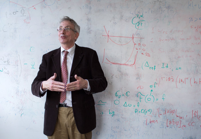 Professor Simon Donaldson stands in front of a white board with mathematics written on it