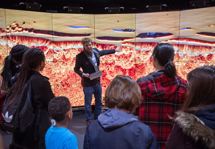 A scientist delivers a talk on Mars, standing in front of a huge digital display