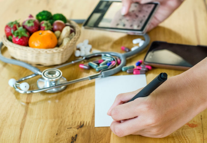 Fruits and vegetables basket, stethoscope, vitamins and smart phone, with hands holding calculator