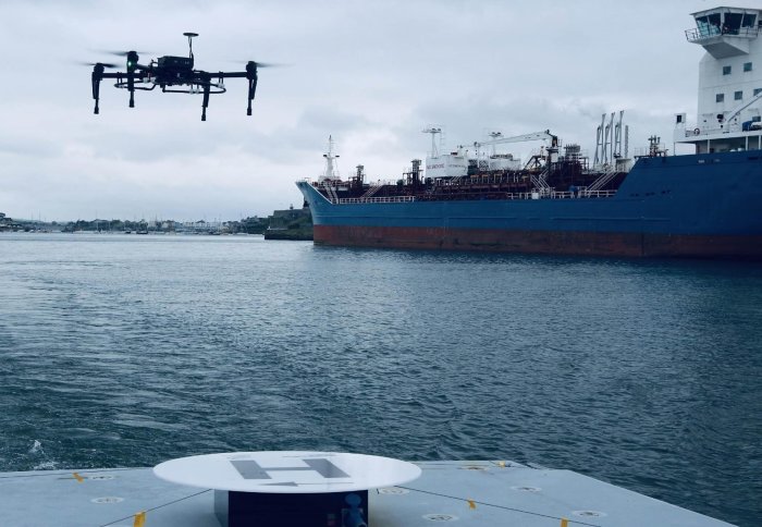 An aerial drone approaching a charging pad on an ocean-going ship