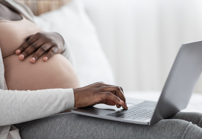 Pregnant woman typing on a laptop