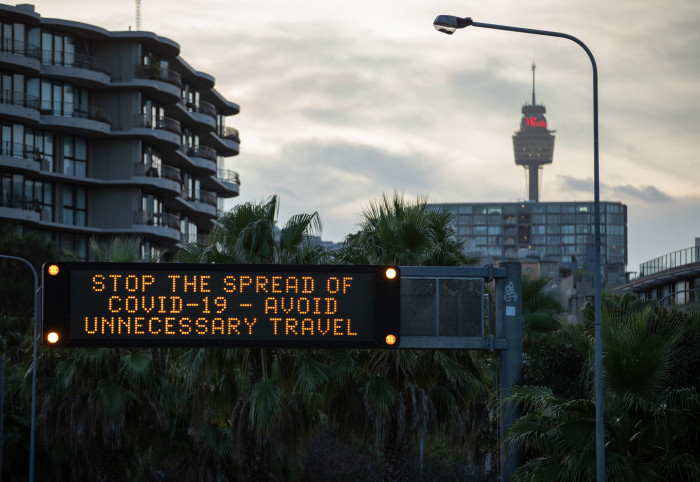 Digital sign in a city that reads: 'Stop the spread of COVID-19 - avoid unnecessary travel'